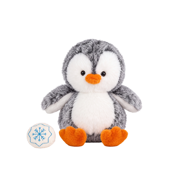 Fluffy plush penguin with grey speckled fur, a white face and tummy, black eyes, and an orange beak and feet, sitting beside a small cream fabric snowball embroidered with a blue snowflake.