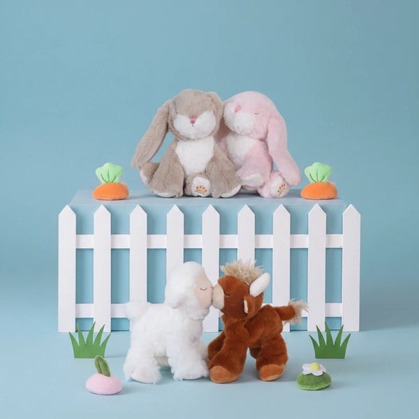 Four plush toys in front of a white picket fence on a blue background
