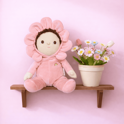 Dinky Dinkums - Dahlia pink flower soft doll from Dinky Dinkum Dolls sitting on a wooden shelf beside a pot of colorful flowers