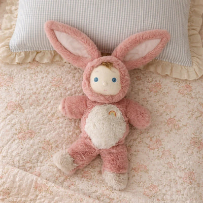 Cozy Day Dinkum - Bunny Pinkie by Cozy Dinkums pink bunny soft doll lying on a floral quilt with blue eyes and floppy ears