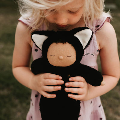 Cozy Cats - Nox black cat soft doll cuddled by a child in a pink dress from Cozy Dinkums