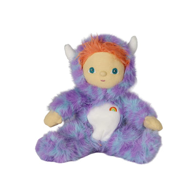 A plush monster doll with a fuzzy purple and blue body, orange hair, white horns, and a white belly patch with a small rainbow, photographed on a plain white background.