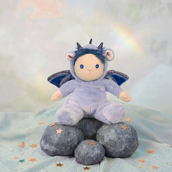 Stuffed toy in a purple outfit with wings and horns on rocks with a starry background