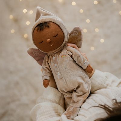 Dozy Dinkum - Fairy Ada soft sleeping fairy doll in a velvet hooded outfit with wings and rainbow detail held gently by a child from Dinkum Dolls