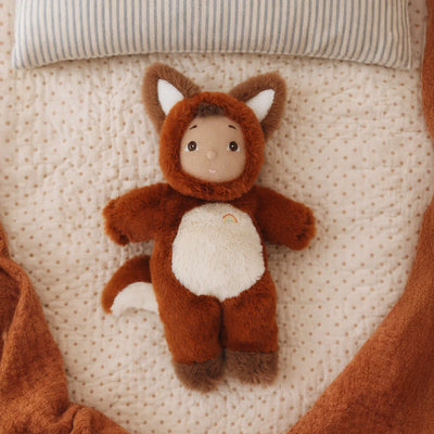 Cozy Day Dinkum - Freddy Fox plush fox soft doll lying on a quilted bed with a striped pillow. Cozy Dinkums toy for imaginative play.