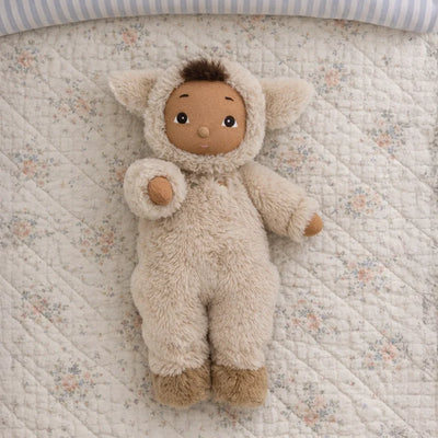 Cozy Day Dinkum - Lamby Tig soft doll in a fluffy lamb outfit lying on a patterned quilt with open eyes and a curly brown tuft from Cozy Dinkums