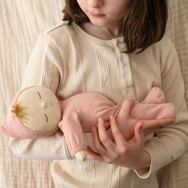Dozy Dinkums - Moppet soft baby doll cuddled in a child's arms featuring a pink outfit and playful imaginative design for gentle nurturing play