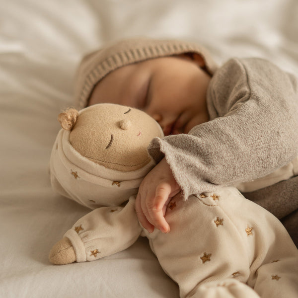 Lullaby Dozy Dinkum - Lyra soft doll in a starry sleepsuit and bonnet cuddled in bed with a sleeping child from Dozy Dinkums