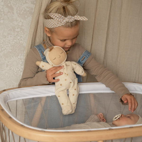 Lullaby Dozy Dinkum - Lyra soft doll cuddled by a child beside a sleeping baby in a nursery bassinet from Dozy Dinkums