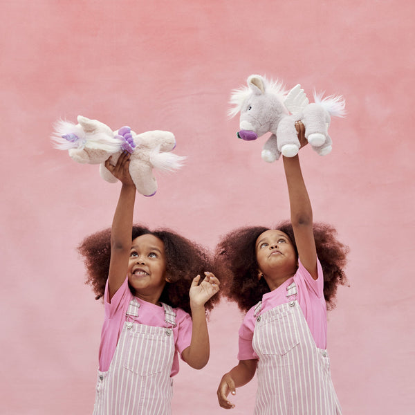 Dinkum Unicorn - Glimmer by Dinkum Unicorns soft plush unicorn toy held aloft by two children during imaginative play