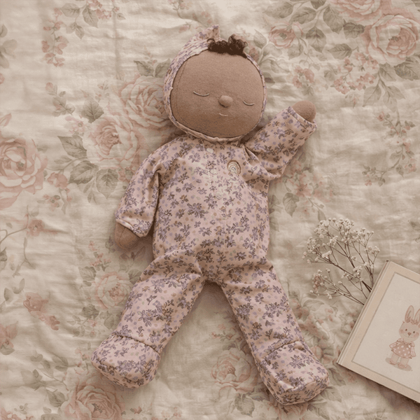 Stuffed doll in floral outfit on a floral-patterned surface