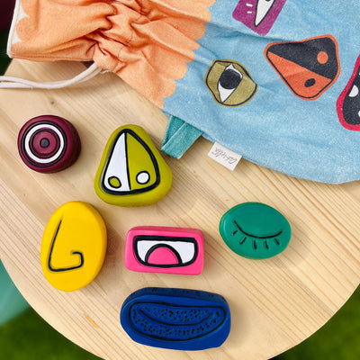 Tubbles Funspressions - Silly Sam by Olli Ella Kids sensory stones with colorful interchangeable facial features arranged on a wooden table