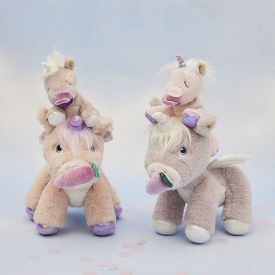 Set of plush unicorn toys stacked on a light background