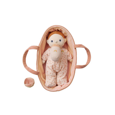 Baby doll in a pink crib on a white background