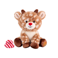 Fluffy plush reindeer with fawn fur and cream spots, a red nose, a smiling cream muzzle, short brown corduroy antlers and hooves, and an embroidered paw-and-rainbow motif on one foot, sitting beside a red and white striped hat.