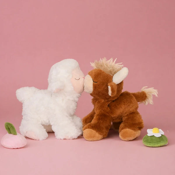 Two plush toys, a white lamb and a brown cow, on a pink background.