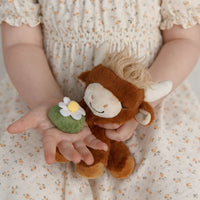 Child holding a plush monkey toy and a felt flower against a floral background