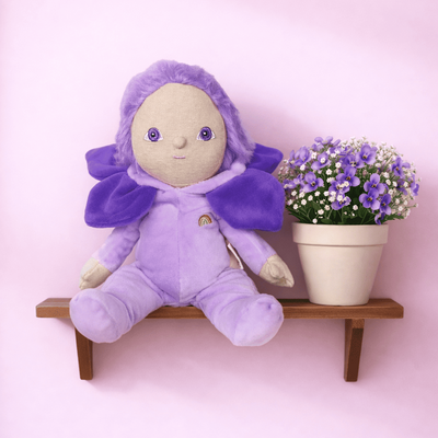 Purple plush toy with a flowerpot on a pink shelf against a pink background