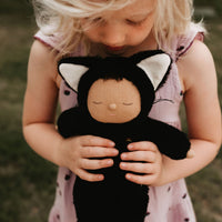 Cozy Cats - Nox black cat soft doll cuddled by a child in a pink dress from Cozy Dinkums