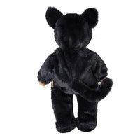 A black plush teddy bear viewed from the back, featuring soft black faux fur, rounded ears, and small tan hands, isolated on a white background.