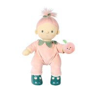 A plush doll with pale skin, green eyes, and pink hair styled like a ponytail with a small green leaf accent. The doll wears a pink outfit with a green collar and holds a small pink apple toy against a plain white background.