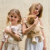 A pink polka dot doll carrier with adjustable straps, perfect for little ones to carry their favorite dolls on adventures. Ideal toddler doll accessory for imaginative parent play.