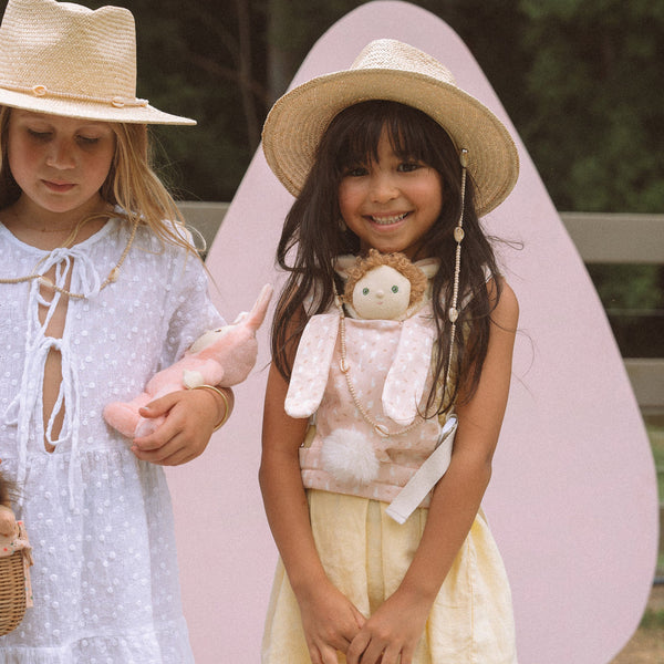 A cozy, bunny-themed pink doll carrier with adjustable straps, perfect for little ones to carry their favorite dolls on adventures. Ideal toddler toy accessory, cuddly easter-themed doll carrier.
