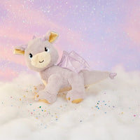 Plush dragon toy with wings on a soft, cloud-like surface with a pastel background