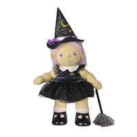 A witch-themed doll with pale skin, lavender hair, and a black pointed hat decorated with a yellow crescent moon and purple ribbon. The doll wears a black dress with a white collar and holds a small black broom against a plain white background.