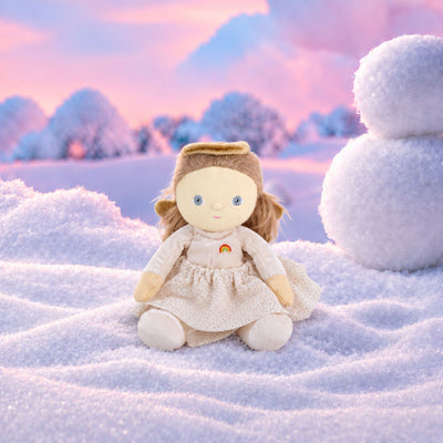 Plush doll dressed as an angel, with fluffy light-brown hair in pigtails, embroidered blue eyes, a gold velvet halo and wings, a cream velvet top with a small rainbow patch, a cream tulle skirt with gold glitter dots, and cream booties.