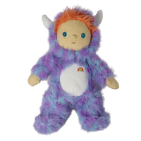 A plush toy doll dressed in a fuzzy purple and blue monster onesie with orange hair, white horns, and a small rainbow emblem on the belly, shown against a plain white background.