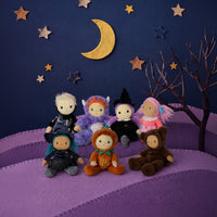 Six plush dolls dressed in Halloween costumes are arranged on a purple felt landscape with a dark blue sky backdrop, gold stars, a crescent moon, and a bare tree.