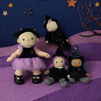 Four witch-themed fabric dolls dressed in black and purple outfits, arranged on a purple hill against a dark blue background with a yellow crescent moon and star decorations.