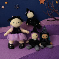 Four witch-themed fabric dolls dressed in black and purple outfits, arranged on a purple hill against a dark blue background with a yellow crescent moon and star decorations.