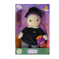 A packaged plush witch doll with a black dress, black hat, pink-purple hair, striped legs, and a small purple moon accessory, shown in a purple and green retail box labeled 'Dumkm Dolls' and 'Angs me dinky witch'.