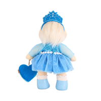 Plush doll with white hair, blue eyes and rosy cheeks, wearing a blue velvet tiara, a sequinned blue dress with sheer sparkly sleeves and a tulle skirt, white frilled socks, light blue shoes, and a blue heart-shaped bag with an embroidered snowflake.