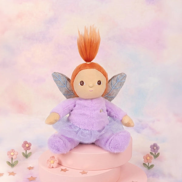 Plush fairy toy with red hair and wings on a pastel background