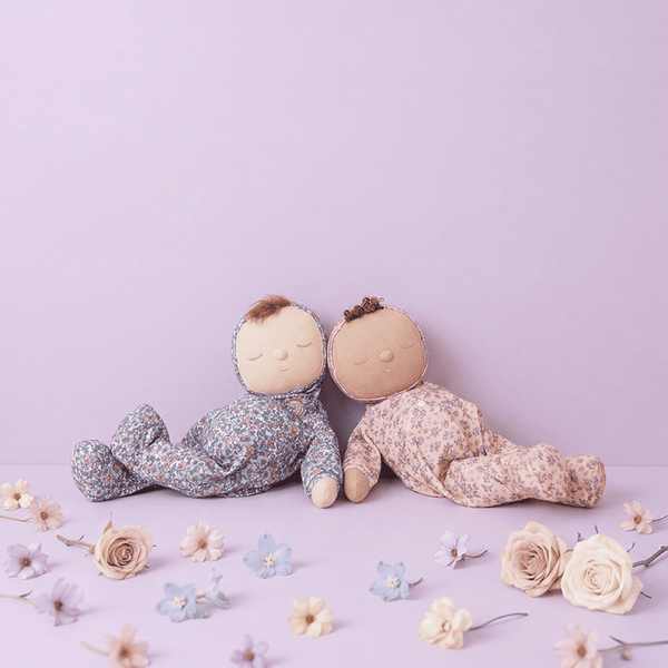 Two soft toys sitting on a light purple surface with flowers around them.