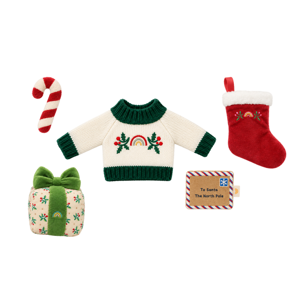 Christmas doll accessory set: a cream knit jumper with green trim and an embroidered rainbow and holly design, a red plush stocking with white fluffy cuff, a red and white striped plush candy cane, a holly-print gift box with a green velvet bow, and a felt “To Santa, The North Pole” letter.