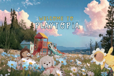 Children's play area with colorful playground equipment and toys in a field of flowers, featuring 'Welcome to Playtopia' text. Dinkum Dolls