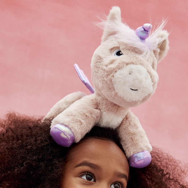 Dinkum Unicorn - Shimmer plush unicorn toy in pink with purple details perched on a child’s head from Dinkum Pets
