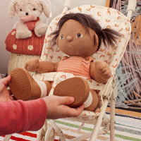 Dinkum Dolls Sollie Stroller Frame with a soft doll seated in a rainbow print stroller as a child holds the doll feet for imaginative play
