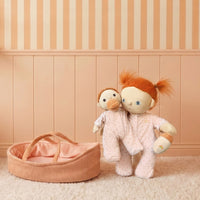 Two plush toys with red hair and a pink basket on a beige carpet with striped wall.