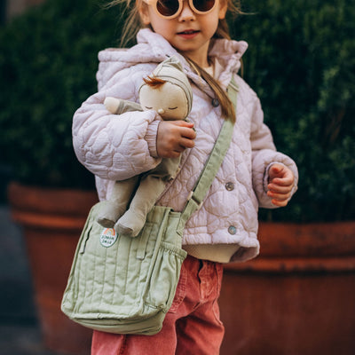 Carrie Convertible Changing Set - Sage by Dinkum Dolls with a child carrying a soft doll in a sage green changing bag