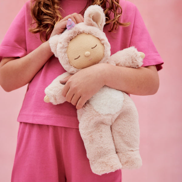Cozy Dinkums - Unicorn - Sugarpie plush unicorn doll with soft blush fur and a purple horn cuddled by a child in pink clothing from Dozy Dinkums