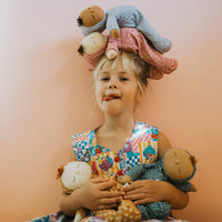 Dozy Dinkum doll with blue velvety onsie outfit. Perfectly weighted doll for calm. Plush doll with blonde hair, perfect for cuddling and interactive doll play.