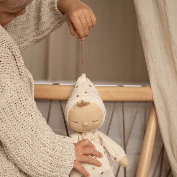 Lullaby Dozy Dinkum - Lyra soft doll hanging from a crib as a child gently holds it in a cosy nursery by Dozy Dinkums