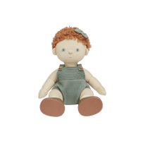 A handmade fabric doll with curly orange hair, a small blue bow, and a sage green overall dress, shown against a plain white background.