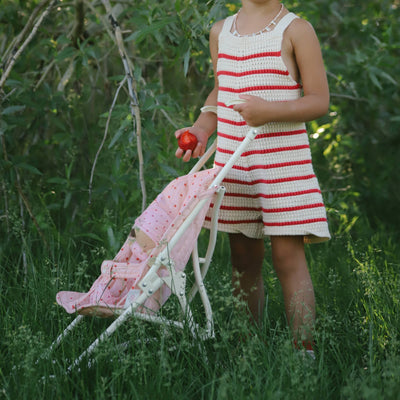 Dinkum Dolls Sollie Stroller Frame in white with a pink doll seat being pushed through grass by a child for imaginative outdoor play