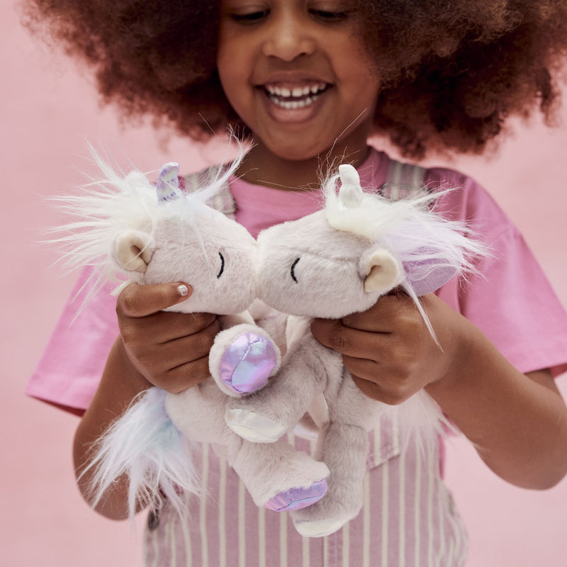 Binky Baby Unicorn - Glitter soft unicorn plush toy held by a smiling child alongside another unicorn with a sparkling horn from Dinkum Pets
